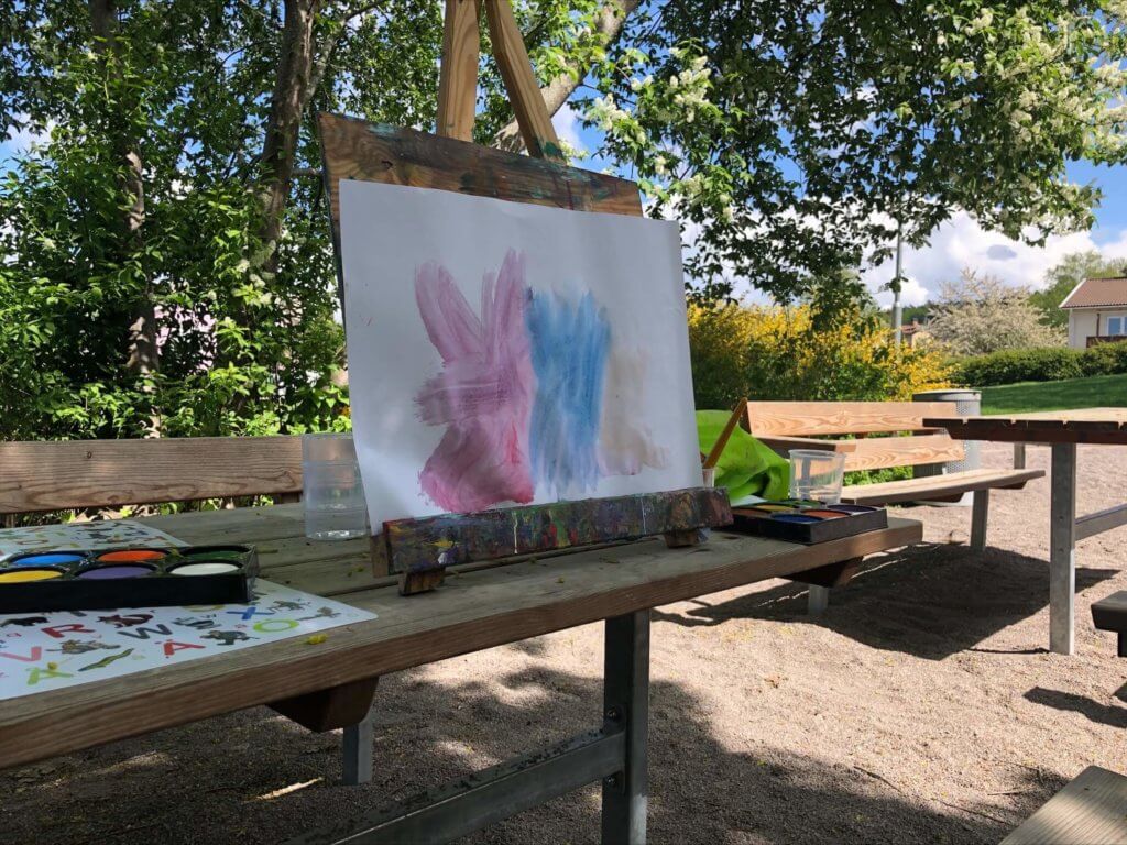Öppen förskola har målargalleri och stafli med färger utomhus i trädgård